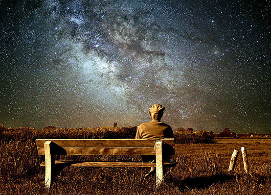 Personne âgée assis sur un banc et regardant les étoiles